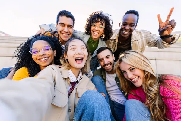 Çeşitli mutlu öğrenci arkadaşlardan oluşan genç bir topluluk birlikte selfie portresi çekiyorlar. Milenyum insanları açık havada eğlenerek eğleniyor. Gençlik, çeşitlilik ve arkadaşlık kavramı.