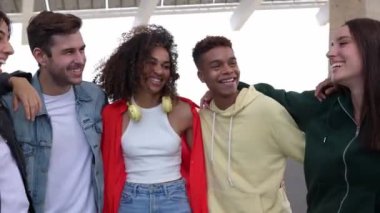 Çok ırklı bir grup genç arkadaş açık havada birlikte gülüyor - Birleşik Milenyum çeşitliliği olan insanlar tatilde eğlenirken birbirlerine sarılıyorlar. Arkadaşlık ve uluslararası toplum kavramı