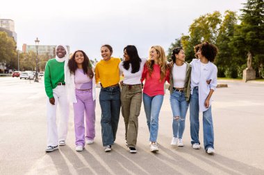 Kadın arkadaş grubu şehir caddesinde birlikte eğleniyor. Dışarıda takılarak birbirine sarılan yedi çok ırklı genç kadın. Gençlik toplumu ve arkadaşlık kavramı.