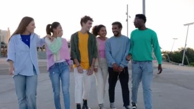 Dışarıda birbiriyle kaynaşan çok ırklı bir grup genç arkadaş. Z jenerasyonu öğrencileri eğleniyor, kentsel arka planda yürürken gülüyorlar. Gençlik, toplum ve çeşitlilik kavramı.
