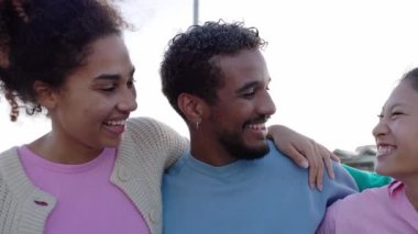 Bir grup mutlu genç insan dışarıda birlikte eğleniyor. Milenyum kuşağı farklı kültürlerden arkadaşlar gülerek birbirlerine sarılıyorlar ve şehrin sokaklarında kaynaşıyorlar..