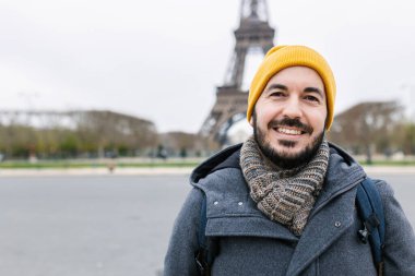 Eyfel Kulesi 'nde dikilen genç bir adamın gülümseyen portresi. Neşeli Avrupalı gezgin Paris 'te tatilin tadını çıkarıyor. Seyahat ve tatil kavramı. Boşluğu kopyala.