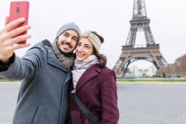 Avrupalı gençler Fransa 'da kış tatilinin tadını çıkarıyorlar. İspanyol yetişkin çift Paris 'teki Eyfel Kulesi' nin önünde selfie çekiyorlar. Turizm ve tatil kavramı.