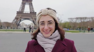 Eyfel Kulesi 'nin üzerinde duran genç yetişkin bir kadının gülümseyen portresi. Neşeli Avrupalı bayan gezgin Paris 'te tatilin tadını çıkarıyor. Seyahat ve tatil kavramı. Boşluğu kopyala.