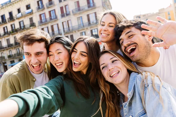 Young group of happy people taking selfie portrait together outdoors. Millennial people enjoying day off at city street. Youth community and friendship concept