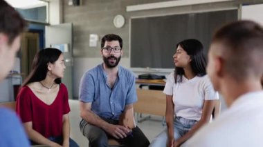Çeşitli lise öğrencileri konferans konuşma grubu sırasında erkek öğretmenle el ele tutuşuyorlar. Takım çalışması, eğitim ve birlik kavramı.