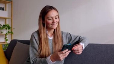 Kredi kartı ve cep telefonu tutan mutlu genç bir kadın banka işlemleri ya da online alışveriş yapıyor. Çevrimiçi ödeme için akıllı telefon kullanan mutlu bayan müşteri. 