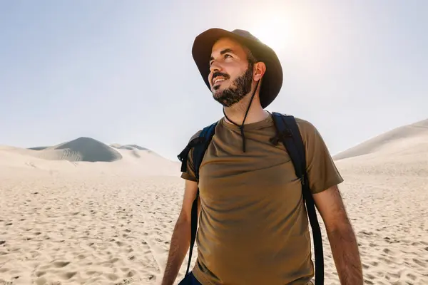 Portrait of young tourist man enjoying vacation in desert. Male holiday maker traveling on North Africa. Holidays and adventure exploration concept.