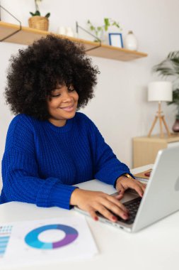 Gülümseyen genç Latin Amerikalı kadın evde dizüstü bilgisayarda çalışıyor. Teknoloji ve iş konsepti.