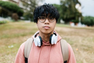 Üniversite kampüsünde kameraya bakan genç Asyalı öğrenci. Eğitim ve insanlar kavramı.