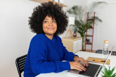 Genç, güzel afro-amerikalı kadın evde dizüstü bilgisayarla çalışıyor. İş ve eğitim kavramı.