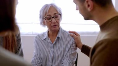 Toplum merkezinde birbirini destekleyen grup terapisindeki farklı insanlarla tanışmak. Yardım ve destek kavramı. Depresyondaki genç adam profesyonel rehberlik toplantısında kıdemli kadın ortağı sakinleştiriyor..
