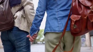 Şehir caddesinde yürürken el ele tutuşan yaşlı çiftlerin arka görüntüsü. Barcelona 'yı gezerken konuşan modaya uygun olgun bir kadın ve erkek. Emeklilik yaşam tarzı ve tatil kavramı.