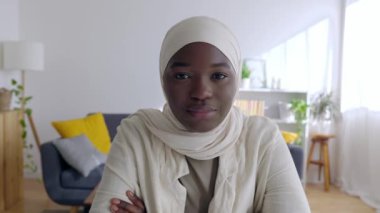 POV ya da dizüstü bilgisayar ekranında beyaz başörtüsü takmış siyah Afrikalı kadının neşeli portresinin evdeki kameraya baktığı görülüyor. Video konferansı ve insanlar konsepti.