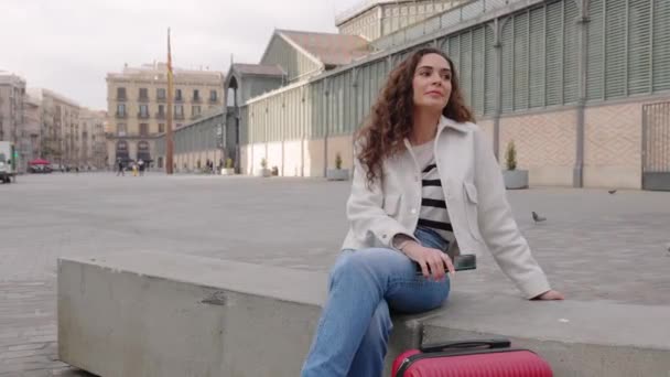 Молода Жінка Дорожнім Багажем Чекає Когось Або Відпочиває Вулиці Сидячи — стокове відео