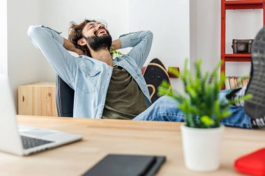 Ofisteki iş gününün bitişini kutlayan mutlu ve rahat genç adam.