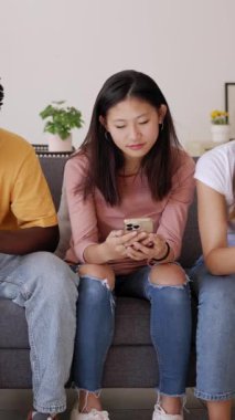 Sosyal medya içeriğini cep telefonundan izleyen bir grup farklı genç insan. Dikey HD video.