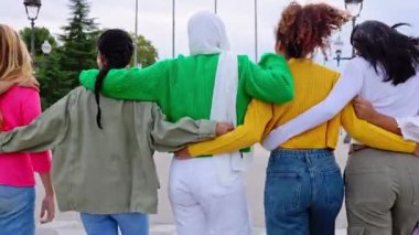 Genç bir grup kadının arka planda birlikte yürümeleri açık havada kucaklaşmaları. Şehir caddesinde birbirine sarılan bayan arkadaşlar. Arkadaşlık ve kadın toplumu kavramı.