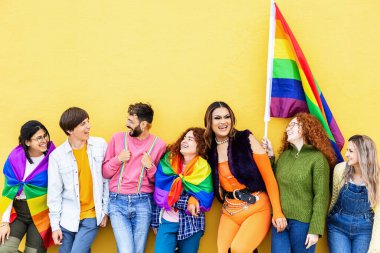 Sarı arka plana yaslanan bir grup genç LGBTQI gay onur festivali gününü kutluyor. LGBT 'nin genç arkadaşları dışarıda eğleniyorlar. Genç homoseksüel toplum kavramı.