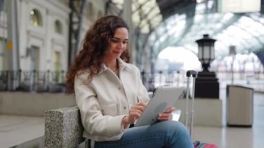 İstasyonda bekleyen dijital tablet kullanan genç bir iş kadını. Seyahat ve iş hayatı konsepti