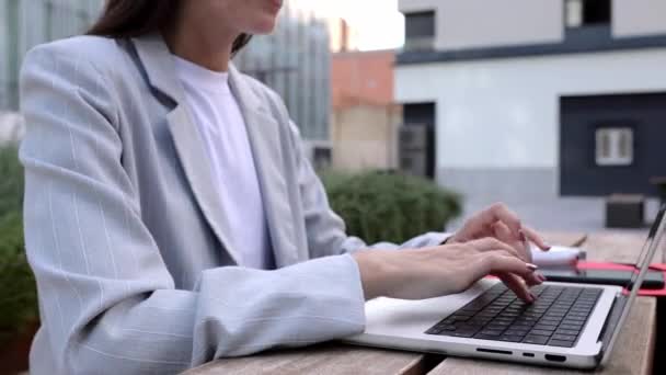 在商业办公大楼外的长椅上 坐在笔记本电脑键盘上打字的女商人的手被关上了 自由职业者和商业生活方式概念 — 图库视频影像
