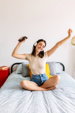 Genç mutlu kadın evde dinlenirken çevrimiçi müzikten zevk alıyor. Boş zaman aktivite konsepti.