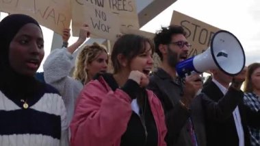 Dünya barışı için yürüyen bir grup aktivist insan. Çeşitli göstericiler savaş ve şiddeti protesto eden pankartlar ve posterler taşıyorlar. Savaş protestosu konsepti yok.
