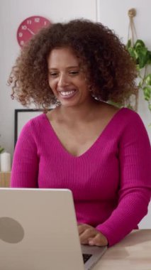 Yaratıcı iş kadını Afrikalı kadın sahibi atölyesinde dizüstü bilgisayarında bir video görüşmesi yapıyor. Ev ofisinden online çalışan mutlu online girişimci kadın. Dikey HD video.