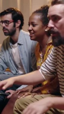 Dikey HD video. Çok ırklı futbol taraftarları TV 'de maç seyrediyor ve zaferi evde kutluyorlar. Dünya Kupası ve spor eğlencesi konsepti