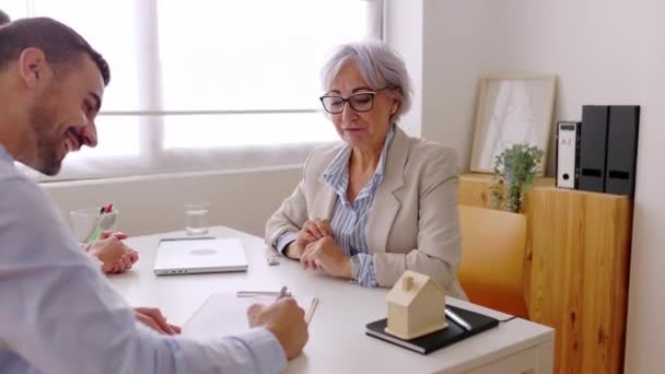 Senior Immobilienmaklerin Mit Einem Jungen Erwachsenen Paar Das Einen Deal — Stockvideo