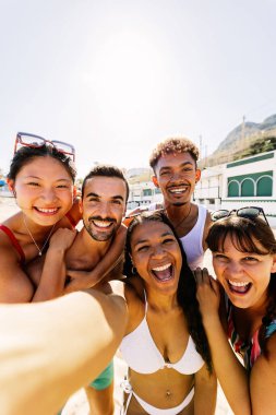Çeşitli insanlar birlikte selfie çektirip sahilde yaz tatilinin tadını çıkarıyorlar. Arkadaşlık ve tatil kavramı.