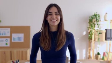 Modern ofis içi işyerinde kollarını kavuşturmuş genç bir iş kadınının gülümseyen portresi. Bağımsız insanlar ve iş hayatı konsepti