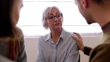 Toplum merkezinde birbirini destekleyen terapi grubu üyeleri. Profesyonel rehberlik toplantısında depresyondaki kıdemli kadın ortağı sakinleştiren gençler. Ruh sağlığı konsepti.