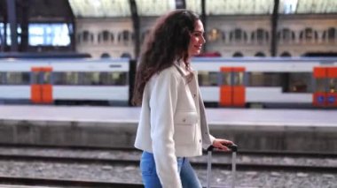Bagajlı genç gezgin kadın vardıktan sonra tren istasyonunda yürüyor. Seyahat ve tatil yaşam tarzı kavramı.