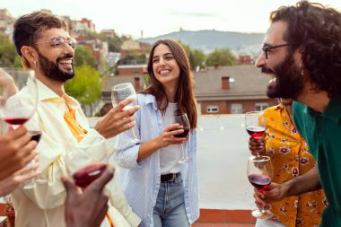 Çok ırklı arkadaşlar yaz partisinde çatı terasında birlikte eğleniyorlar. Milenyum insanları gülerek, yemek yiyerek ve dans ederek eğleniyor..