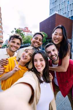 Şehir caddesinde selfie çektirirken eğlenen bir grup genç insan. Milenyum öğrenci arkadaşları dışarıda gülüyor. Gençlik toplumu kavramı.