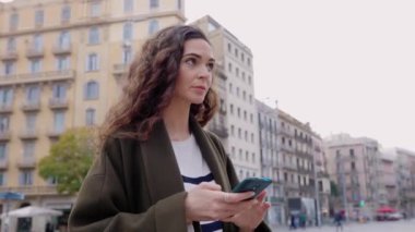 Şehirdeki akıllı telefondan haritada gezinen genç bir kadın bir yer arıyor. GPS navigasyon kavramı.