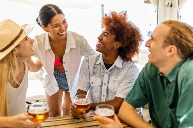 Bir grup genç arkadaş yaz tatilinde soğuk bira içerek plaj partisinden zevk alıyorlar.