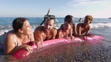 Şişme minderli bir arkadaş grubu yazın denizde eğleniyor. Tatil yaşam tarzı ve arkadaşlık kavramı.