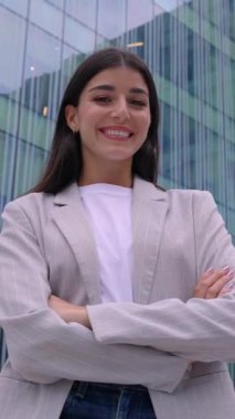 Ofis binasının önünde duran çapraz kollu genç iş kadınının dikey HD özgüven portresi. Liderlik, vizyon ve güçlendirme konsepti. 9: 16 ekran videosu.