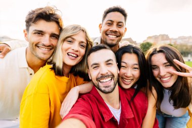 Milenyum arkadaşlarıyla birlikte dışarıda eğlenen genç topluluk konsepti. Milenyum insanlarından oluşan çeşitli bir grup selfie çekiyorlar. Şehir parkında boş vakitlerin tadını çıkarıyorlar..