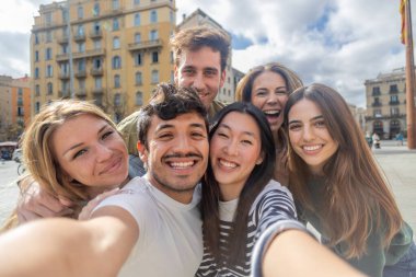 Bir grup genç, şehir caddesinde selfie çektirirken tatilde eğleniyor. Arkadaşlık ve gençlik toplumu kavramı.