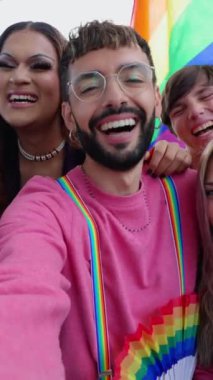 Genç LGBT grubunun eşcinsel geçit töreninin tadını çıkardığı dikey video. Lezbiyen ve eşcinsel arkadaşlar birlikte LGBTQI festivalini kutluyorlar..