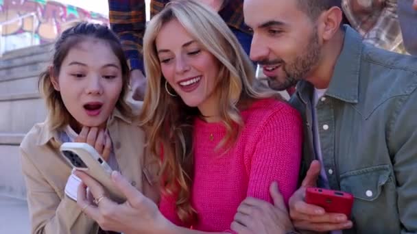 Молодые Многорасовые Друзья Веселятся Глядя Экран Мобильного Телефона Сидя Улице — стоковое видео
