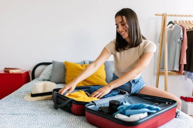 Genç mutlu kadın yaz tatili için bavul hazırlıyor. Seyahat ve tatil kavramı.