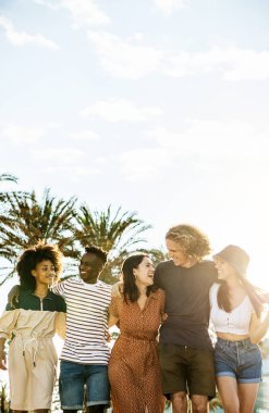 Yazın birlikte yürüyen bir grup genç arkadaş. Çeşitli insanlar tatilde sahilde takılırken birbirlerine sarılıyorlar. Tatil yaşam tarzı ve arkadaşlık kavramı.