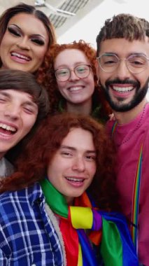 LGBT hakları için çalışan genç aktivistlerin dikey HD portresi gökkuşağı bayrağıyla kameraya gülümsüyor. Eşcinsel ve lezbiyen topluluğunun çeşitli insanları gay gurur ayını kutlayarak gülüyor.