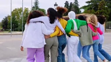 Genç bir grup kadının arka planda birlikte yürümeleri açık havada kucaklaşmaları. Şehir caddesinde birbirine sarılan bayan arkadaşlar. Arkadaşlık ve kadın toplumu kavramı.