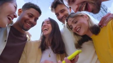 Genç bir grup insan dışarıda cep telefonuyla eğleniyor. Akıllı telefon uygulamasında sosyal medyadan keyif alan neşeli öğrenci topluluğu.