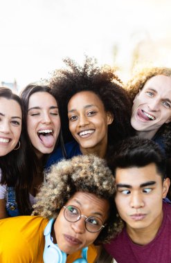 Dışarıda birlikte eğlenen genç ve mutlu arkadaşların dikey portresi. Milenyum çeşitliliği olan insanlar şehrin sokaklarında komik suratlar yapıyor.